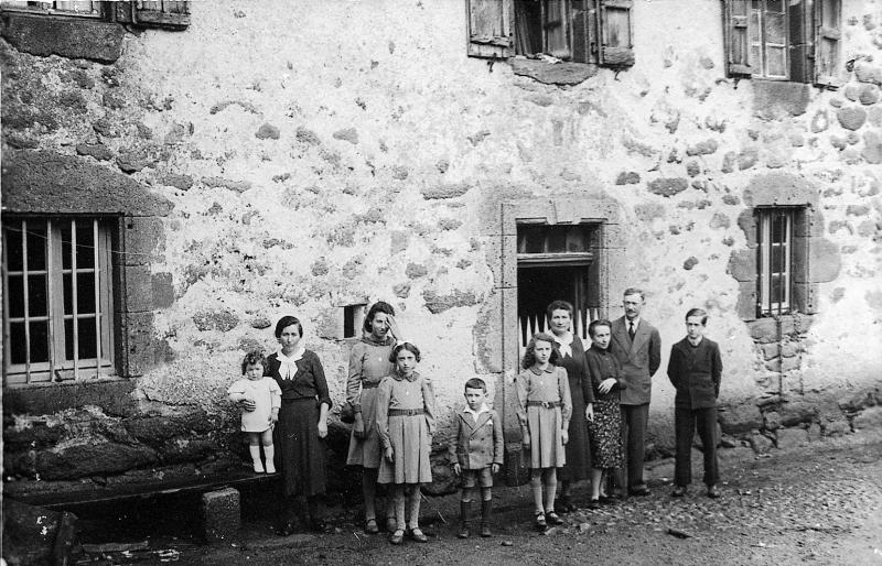 Famille devant façade de maison (ostal), en Aubrac (secteur de Laguiole)