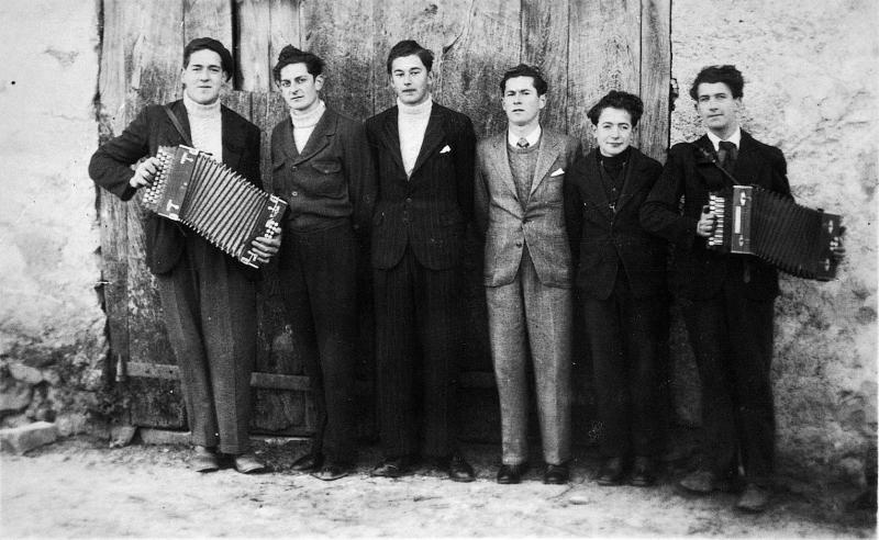 Conscrits et deux accordéonistes (acordeonistas) devant une porte de grange, en Viadène (secteur de Saint-Amans des Cots) 