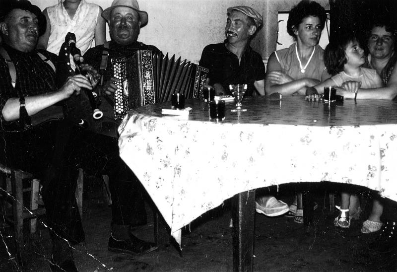 Joueur de cabrette (cabretaire), accordéoniste (acordeonista) et personnes attablés au café Chaliès, 1954