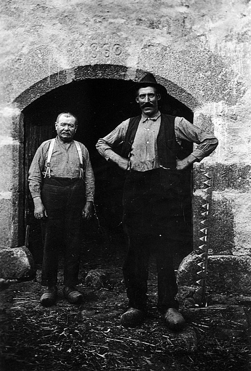 Deux hommes en sabots (esclòp) devant porte d'étable, en Viadène (secteur de Saint-Amans des Cots), 1936