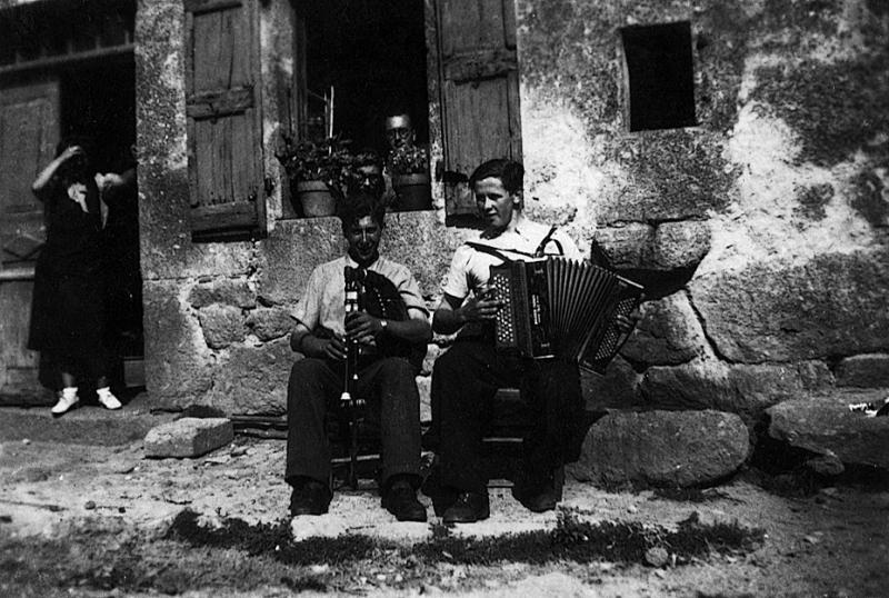 Duo masculin accordéon (acordeon) et cabrette (cabreta) devant la maison (ostal) Pélissier, 11 juillet 1943
