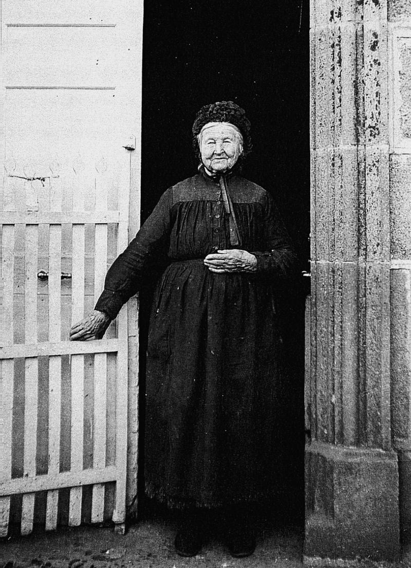 Vieille dame avec coiffe sur pas de porte (pòrta), en Viadène (secteur de Sainte-Geneviève sur Argence), 1933