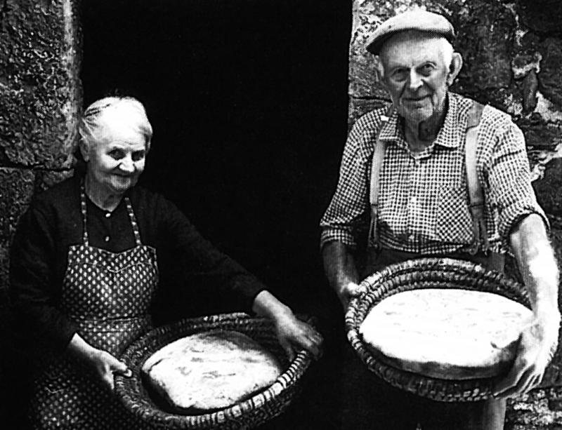  Couple montrant deux miches (tortas) de pain dans des corbeilles (palhassetas), en Barrez (secteur de Mur de Barrez)