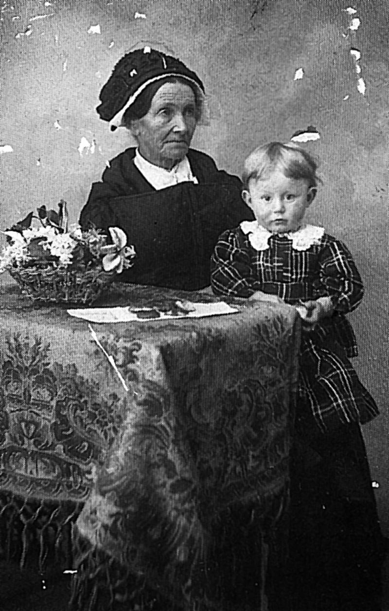 Vieille dame avec coiffe (còfa) attablée et jeune garçon, en Barrez (secteur de Mur de Barrez), vers 1915