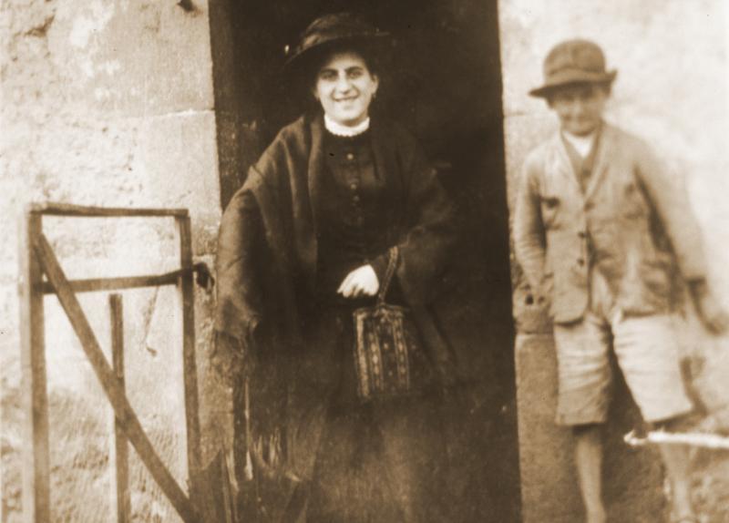 Femme costumée et jeune garçon sur un pas de porte, à Ladignac