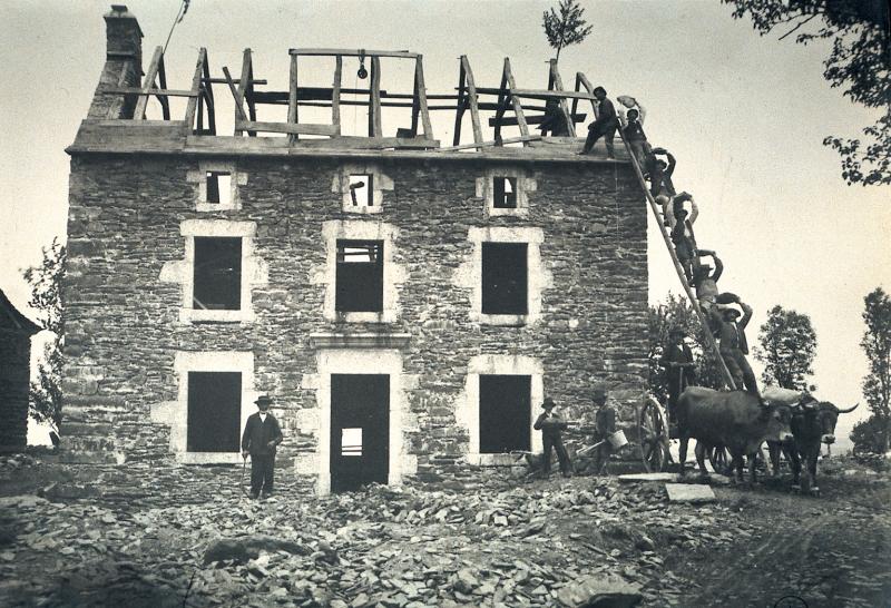 Ouvriers (obrièrs) faisant la chaîne (« far Guilhaume ») sur une échelle (escala) pour monter les pierres de construction d'un mur-pignon (capial) et paire de bovidés (parelh) attelés, à Aunac, 1924