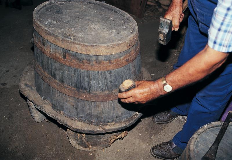  Homme frappant les cercles (ceucles) en fer d'une comporte (semal) ovale retournée, août 1994