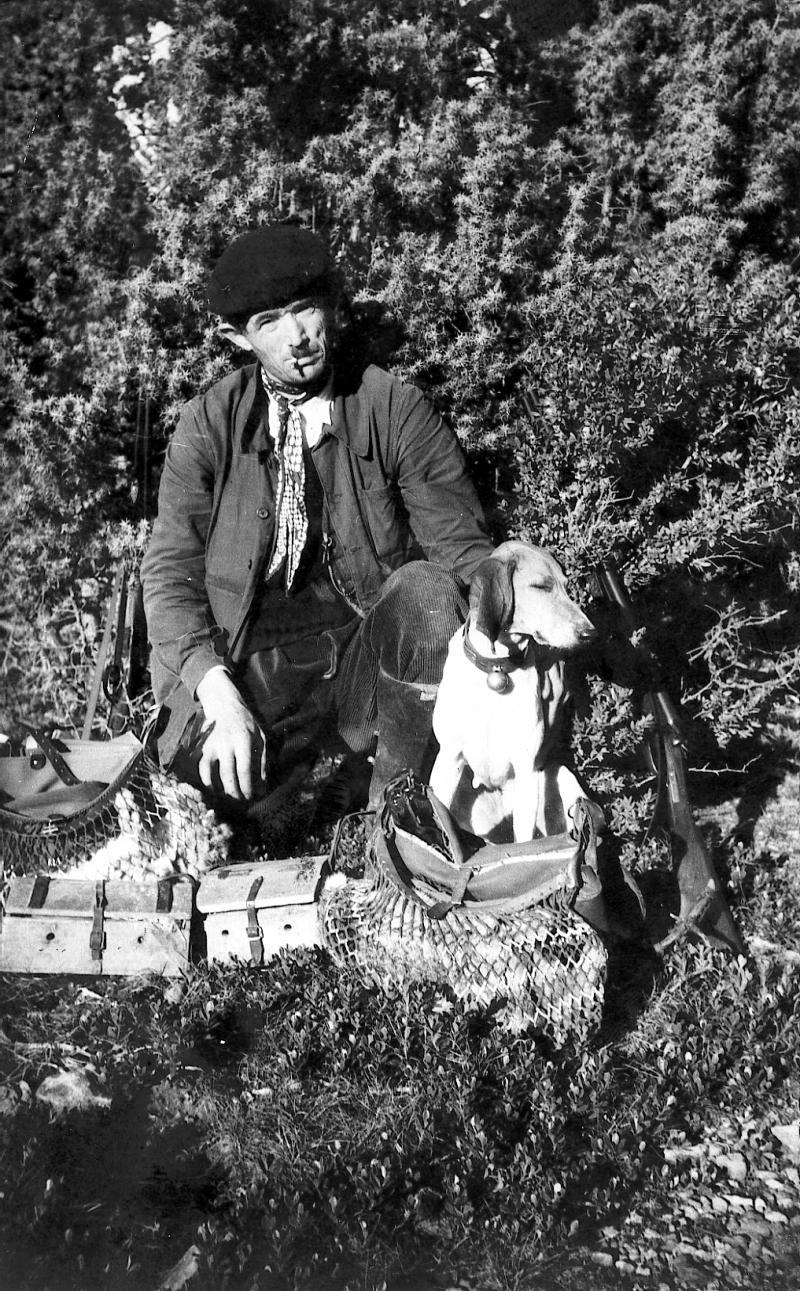 Chasseur (caçaire), chien (can), gibecières et cages à furet (fura) devant genévrier (cade, ginibre)