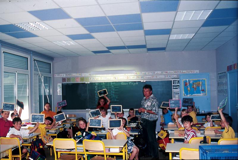 Ecoliers (escolans) et enseignant (mèstre) dans la salle de classe de l'école (escòla) bilingue Joan-Bodon, a La Primaube, mardi 1er juin 2000
