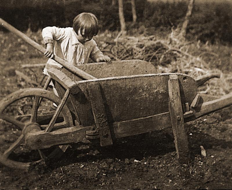 Jeune enfant (dròlle, enfant) et brouette (carriòla) en bois dans un verger (verdièr), à Puech Rouget, 1934