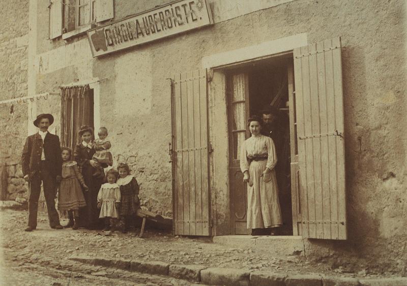 Famille sur un trottoir et aubergistes (aubergistas) sur le pas de porte de leur commerce, vers 1902