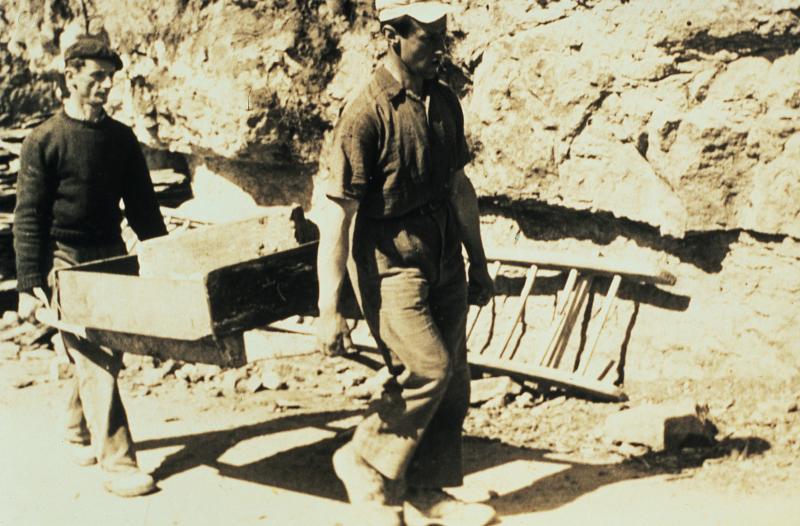 Deux hommes transportant une pierre (pèira) avec un bard ou une civière (baiard, embalais), 1955