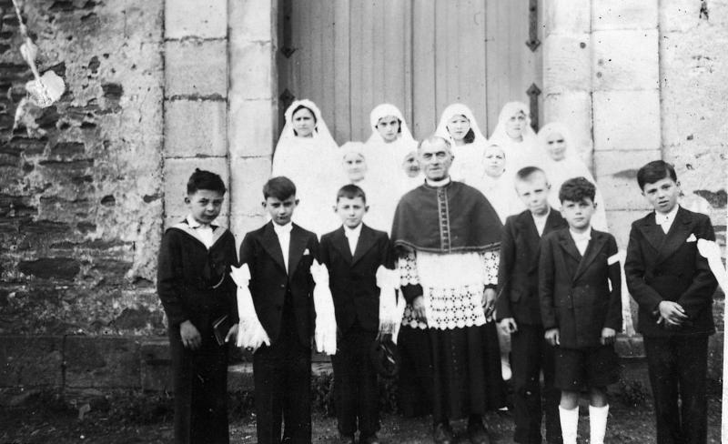 Communiants en costume, communiantes en aubes et curé (curat) en surplis, 1938