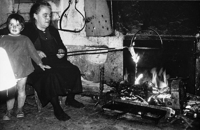  Jeune fille et femme flambant au capucin (flambador) un lièvre (lèbre) cuit à la broche (aste) et au feu de bois, à Saint-Pierre de Gourjas, 1965