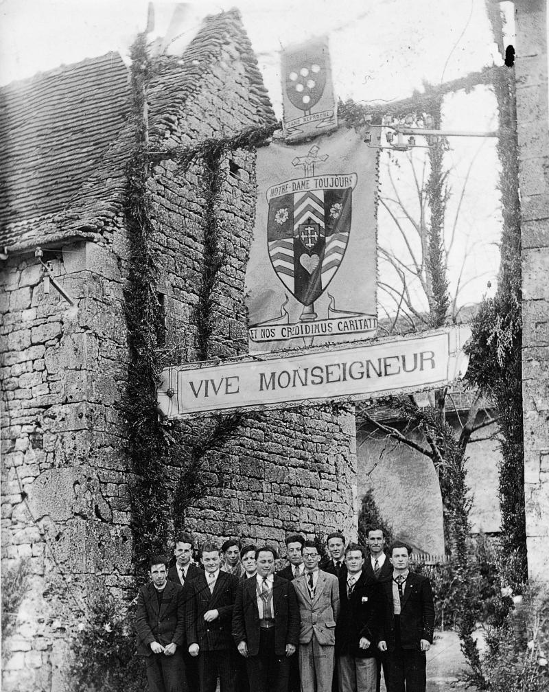  Douze jeunes hommes sous une banderole Vive Monseigneur, avril 1950