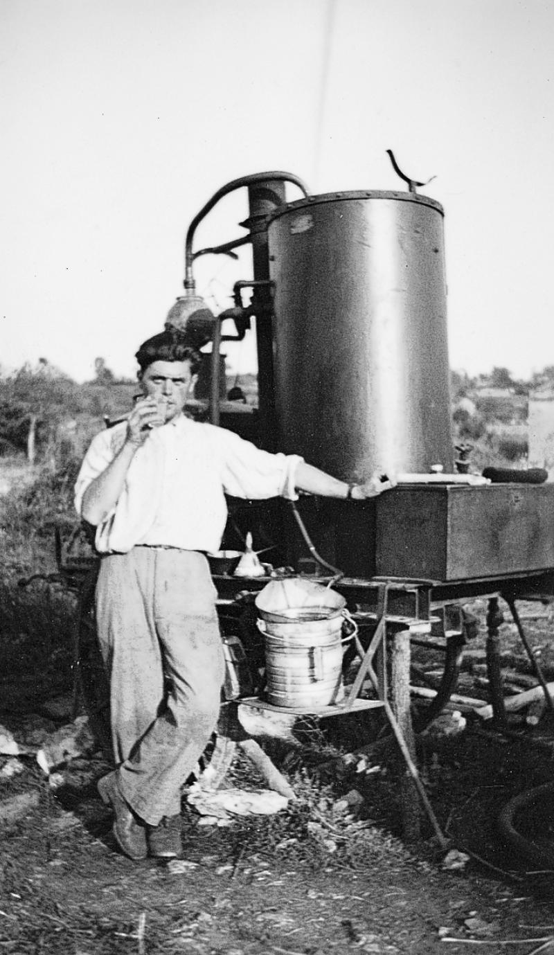 Homme buvant devant un alambic, au Grès, 1955