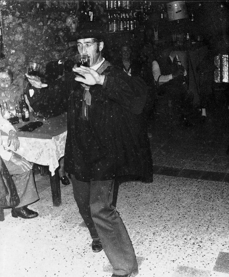 Homme costumé dansant avec deux verres remplis de vin sur les mains et joueur de cabrette (cabretaire), dans le Villeneuvois (secteur de Villeneuve d'Aveyron), 15 septembre 1971