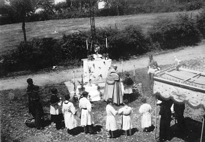 Enfants de chœur (clergues), curé (curat) et fabriciens (fabricians) sous un dais devant une croix (crotz) servant de chapelle-reposoir (capèla), à Blauzac, 14 juin 1942