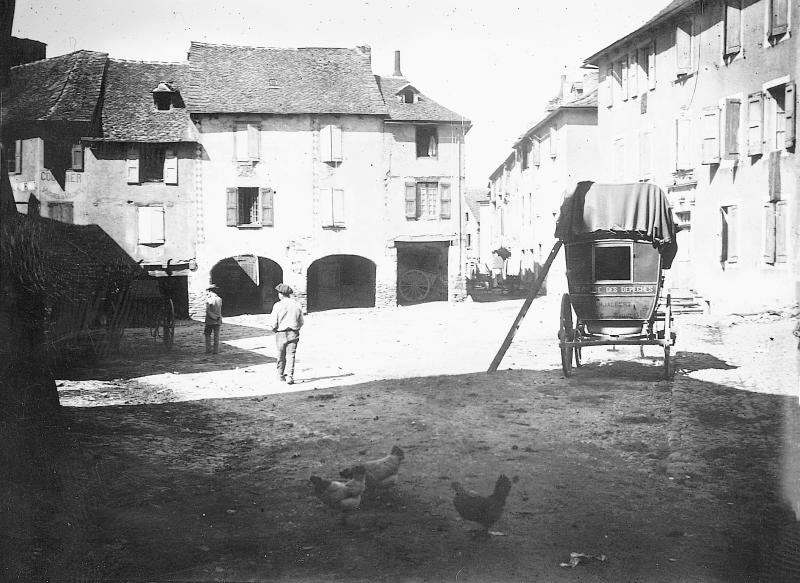 Chars (carris), villageois (vilatjors), poules (polas) et diligence (diligéncia) sur la place aux arcades (gitats)