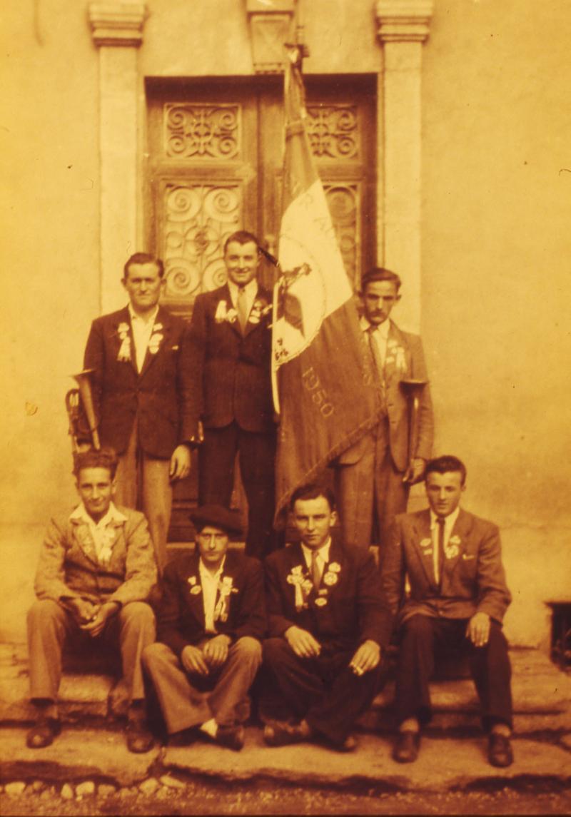 Conscrits, dont un avec un clairon (claron), devant une porte d'entrée de maison (ostal), 10 octobre 1949