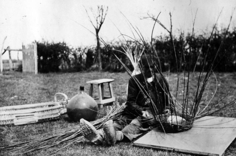 Homme confectionnant l'habillage en osier (vim) d'une bonbonne (bombona) dans une prairie (prada, prat)