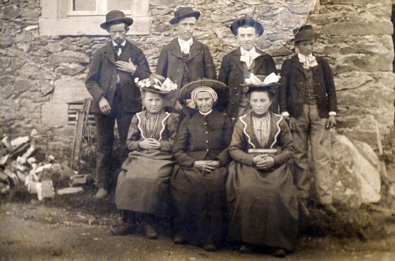 Famille en habits (vestit) traditionnels devant une façade de maison (ostal)