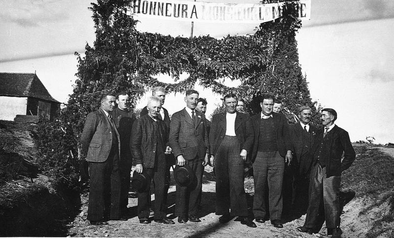 Villageois (vilatjors) devant une banderole “Honneur à Monsieur le Maire” pour la plantation d'un mai