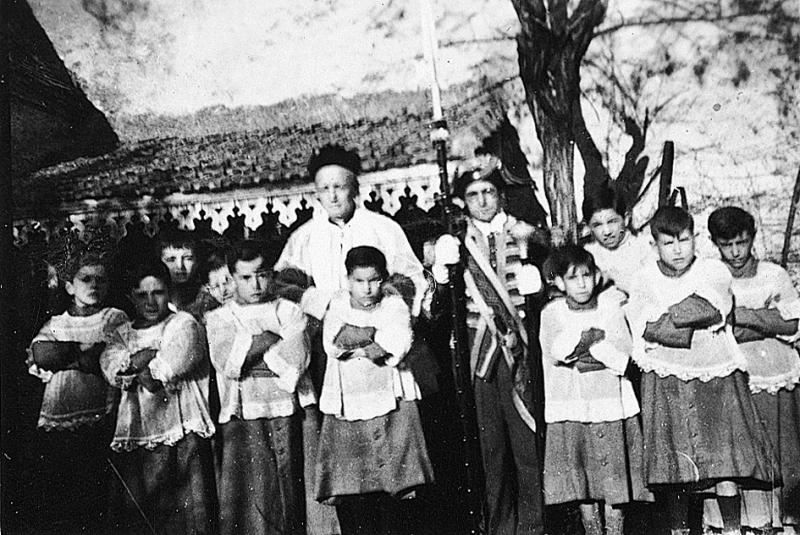 Enfants de chœur (clergues), curé (curat) et suisse avec bâton (baston, pal) processionnel pour la Fête Dieu (Fèsta Diu), 1945-1950
