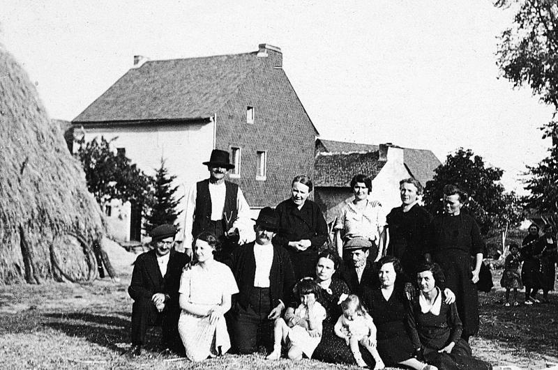 Famille devant un gerbier (plonjon) et une maison (ostal) au pignon (capial) recouvert d'ardoises, à La Vernhe, vers 1937