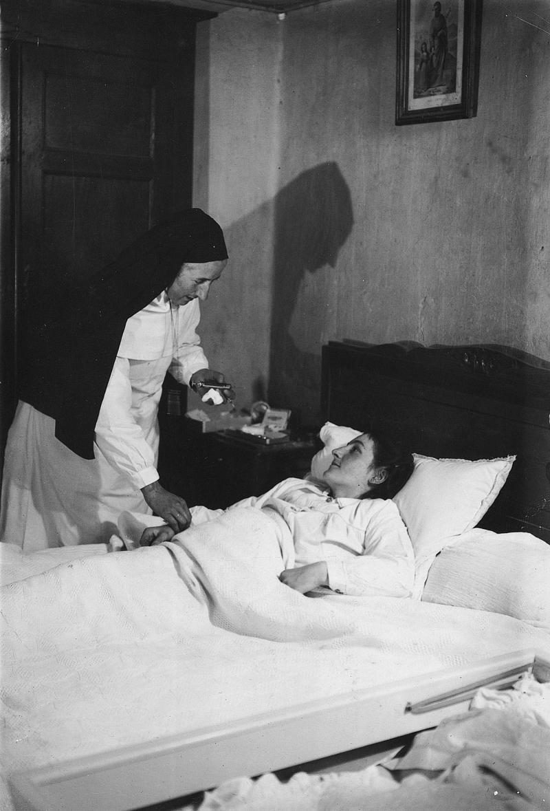 Religieuse (sòrre, sur) prenant le pouls à une femme alitée, à La Crouzette, 1950