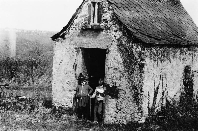 Deux enfants (dròlles, enfants) sur le pas de porte d'une cabane (cabana, ostalon) de vigne, aux Vignes, 1er novembre 1983