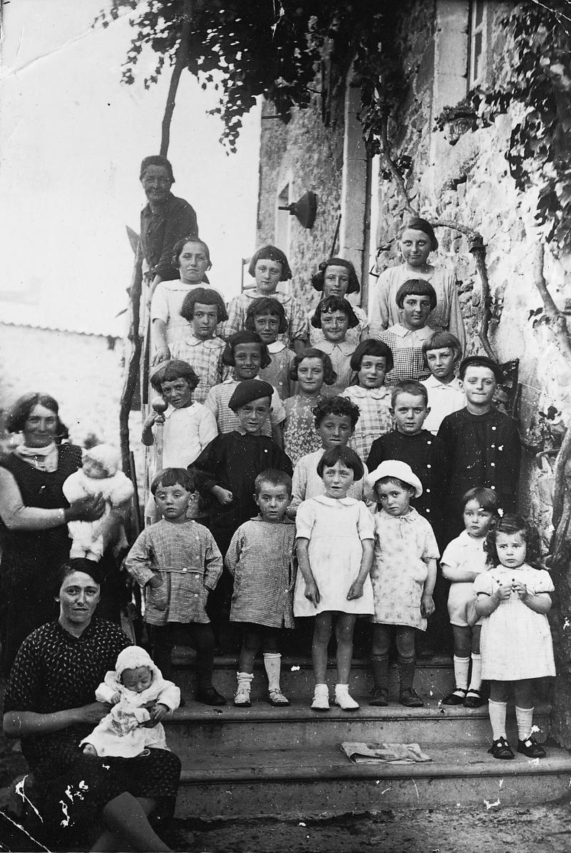 Femmes (femnas) et enfants (dròlles, enfants) dans les escaliers d'une maison (ostal) après la bénédiction du pain, à Montloubet, août 1938