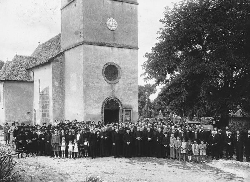 Paroissiens (parroquians), curés (curats) en soutane et évêque (evesque) devant l'église (glèisa) pour un jubilé, à Teulières, 15 septembre 1952