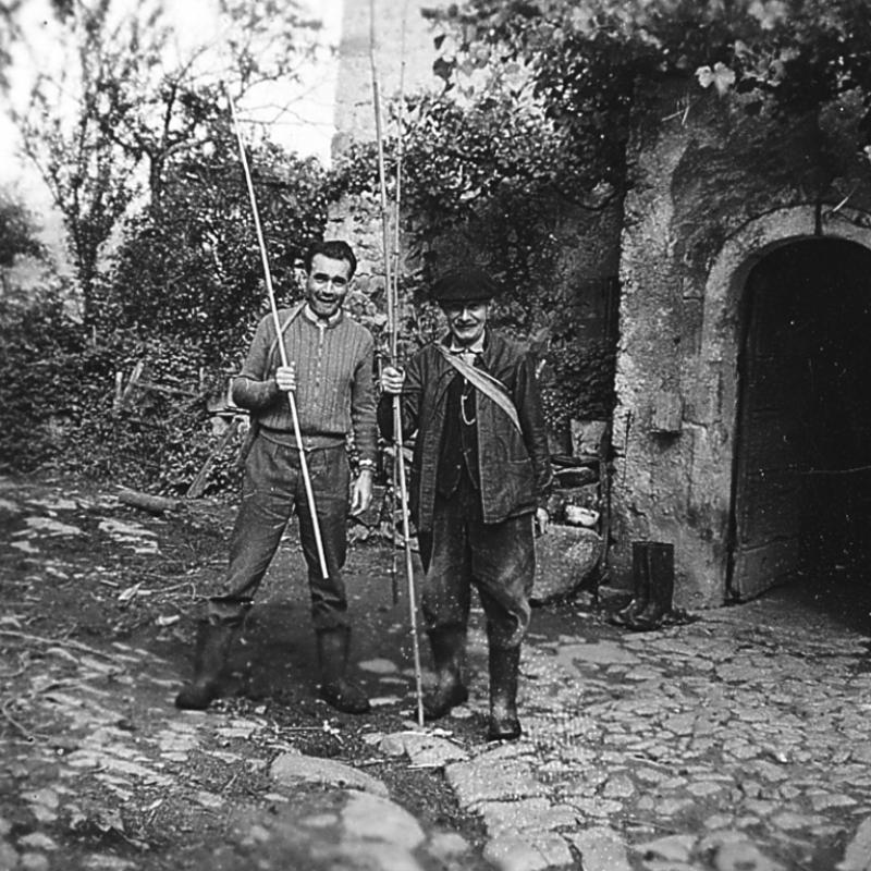 Deux pêcheurs (pescaires) avec des cannes à pêche devant une porte (pòrta) de cave (cava), au Rieu, juillet 1958