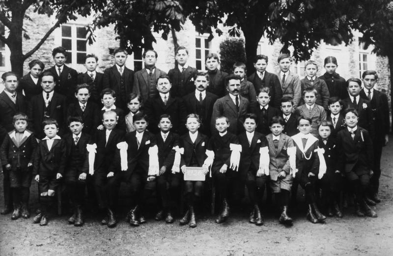 Communiants avec brassard, écoliers (escolans) et maîtres (mèstres) de l'école (escòla) libre ou privée des garçons, à Ceignac, 1926