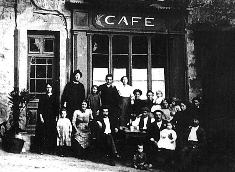 Familles devant une devanture (veirina) ou attablées devant un café (cafè), place de l'église, 1918