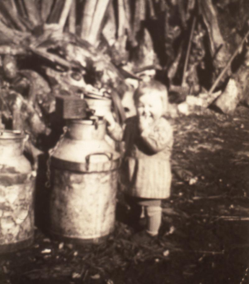 Enfant (dròlle, enfant) devant trois bidons de lait en fer blanc, en Ségala (secteur de Cassagnes Bégonhès), 1943
